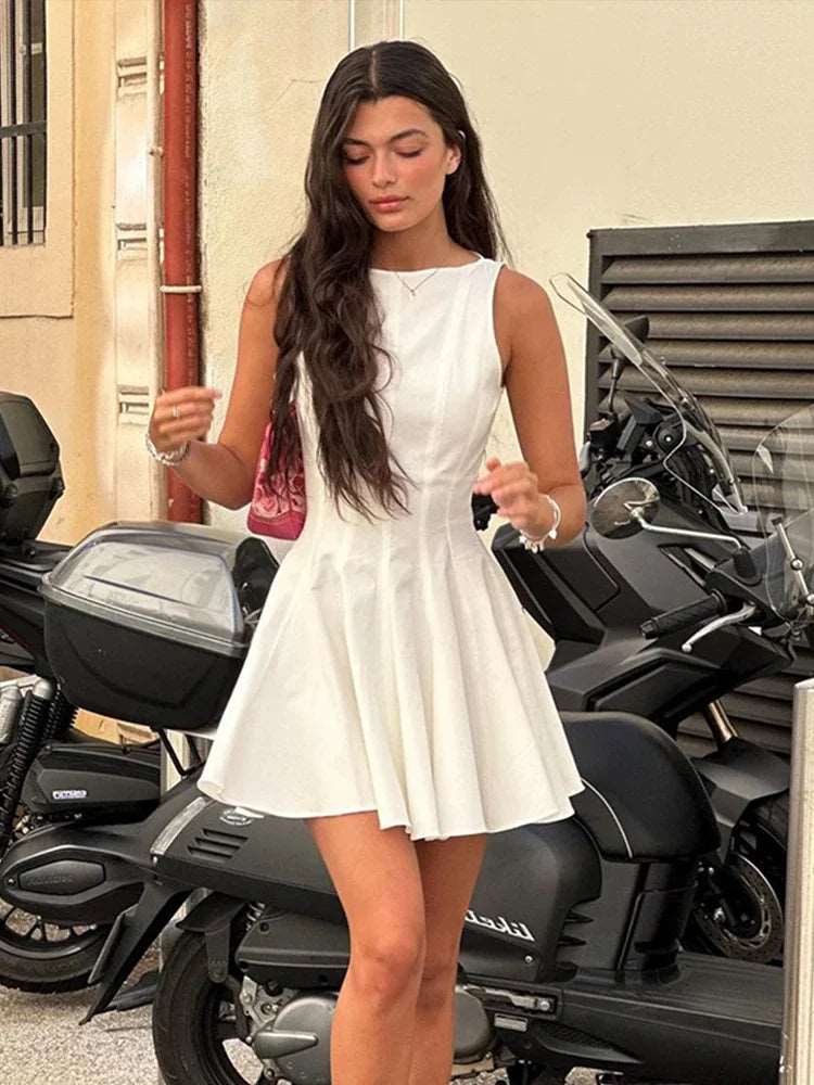 Découvrez notre robe courte plissée style Empire. Cette robe blanche sans manches, de coupe A-line, est idéale pour une mode estivale chic et tendance. NEITH