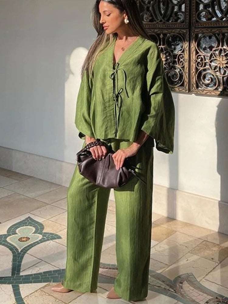 Adoptez un style décontracté avec notre ensemble vert à deux pièces. Composé d'une chemise à manches évasées et lacets et d'un pantalon à jambes larges, il offre un look moderne et élégant pour chaque occasion.